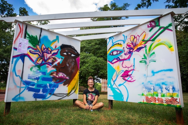 Makayla Binter sitting between her Mural Project