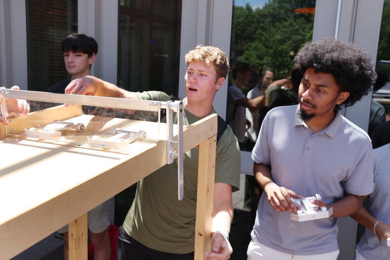 a group of young men race miniature cars outdoors