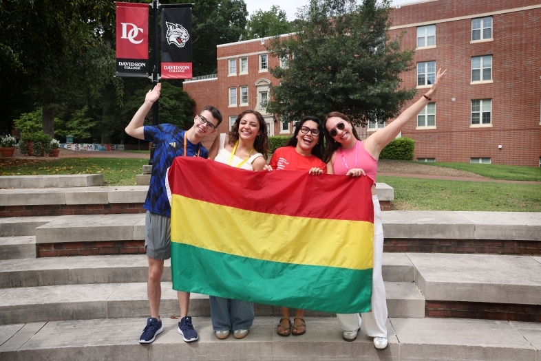 Four students holding a flag that is red, yellow, and green