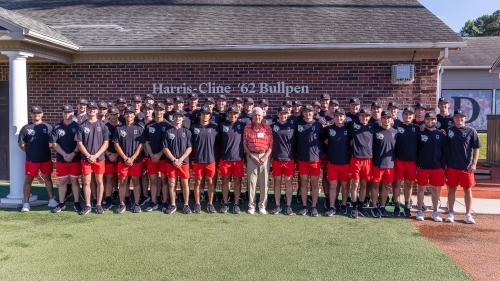 Tom Harris ’62 stands in front of the Harris-Cline Bullpen with Davidson College baseball players