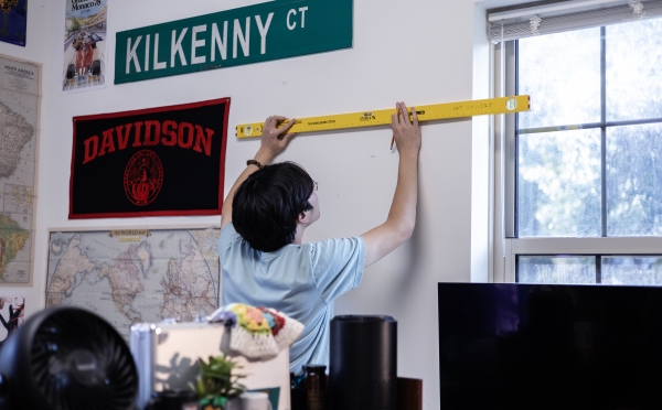 Student Hanging Artmate Art on Dorm Wall