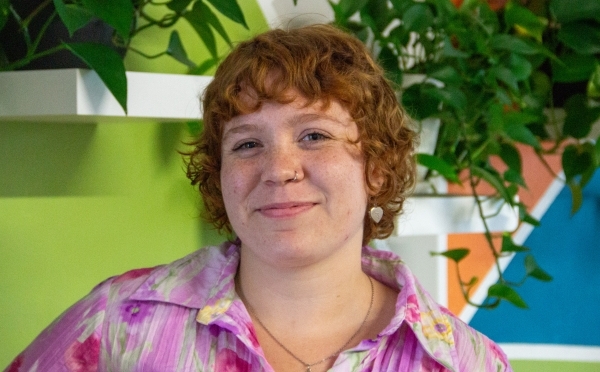 a young white woman with red hair wearing a pink top and smiling