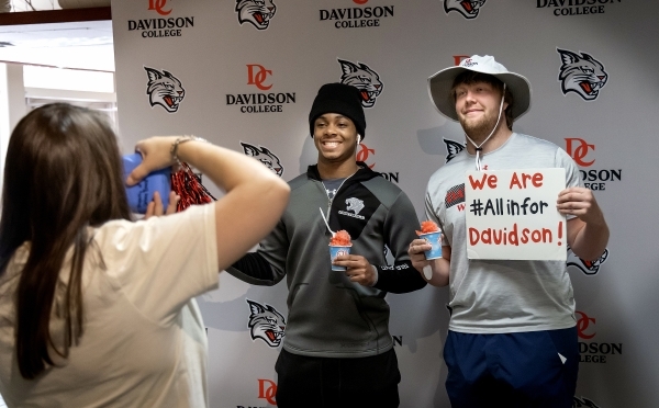 Two students pose with sno-cones and Davidson-themed signs at All In for Davidson