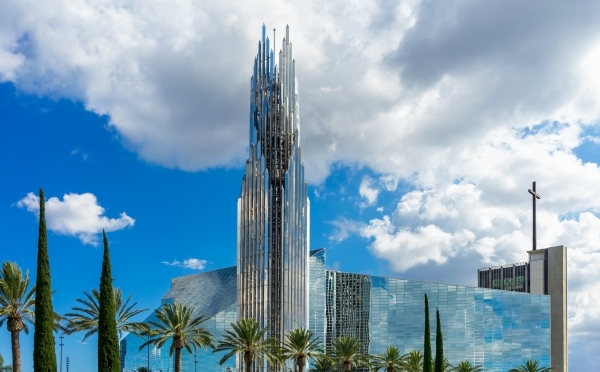 a large glass building surrounded by palm trees on a sunny day