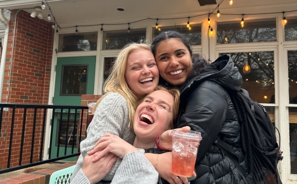 a group of young women smiling and holding a coffee