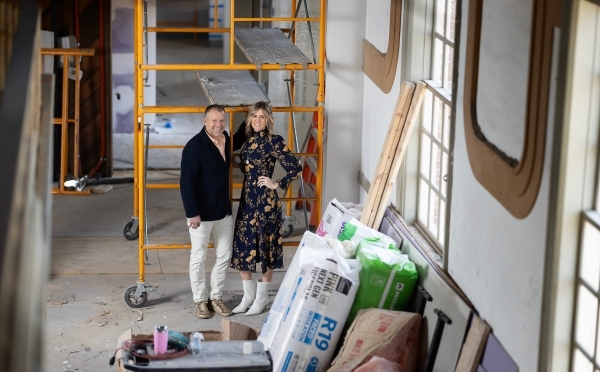 a young white couple stand together in a church under renovation