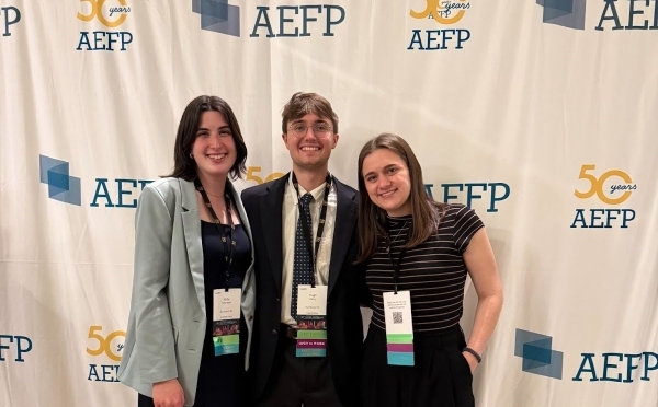 a group of three students in business casual smile together at a conference