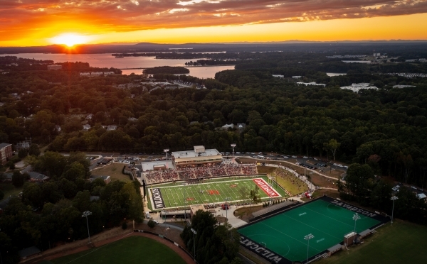 an aerial view of a football stadium as the sun sets in the distance over a lake