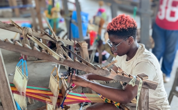 a young person works at a loom 