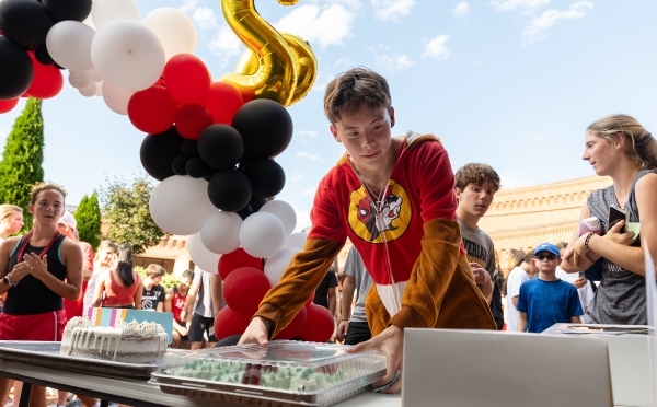 Student in Buc-ees pajama onesie picks a cake after finishing the race