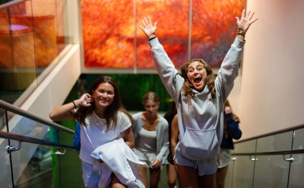 young women jump and smile in a museum