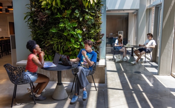 two people meet over laptops and notebooks in a modern academic space
