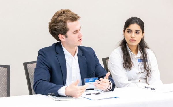 two students discuss at a roundtable while wearing business attire