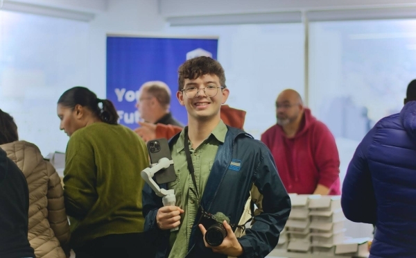 a young man with a camera and phone works media at an event