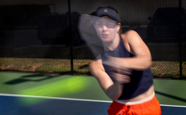 a young woman swings at a pickleball on a court