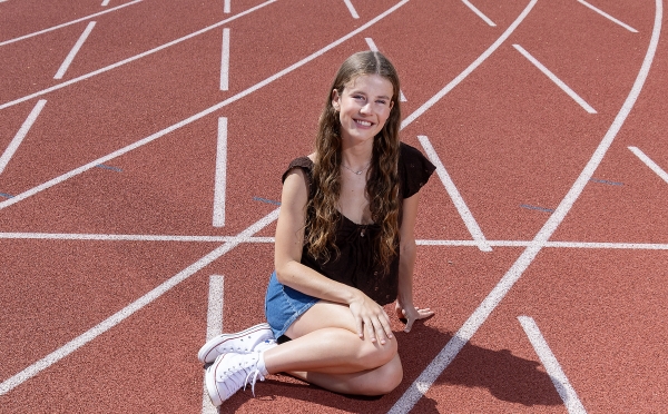A young woman with long brown hair on a track field