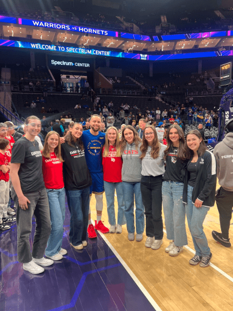Davidson students with Steph Curry on a basketball court