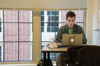 Study room of dorms where student does homework on his laptop