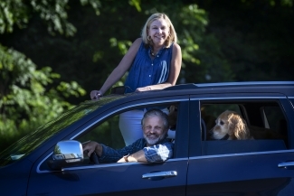 Family with Dog smiling through car 