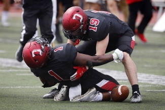 Two Davidson football players helping each other up