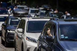 Cars Line Up for Move In, person in car does thumbs up out of passenger window