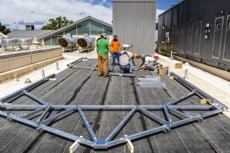 Group of people begin constructing greenhouse on roof of Wall Center