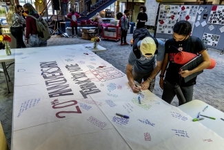Two students sign thank you note at the 20th anniversary celebration