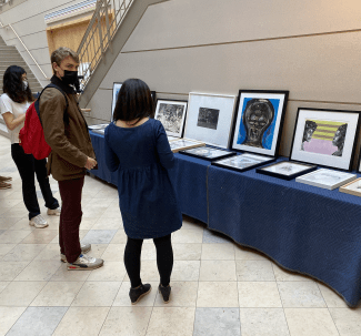 students and director around table of artwork displayed
