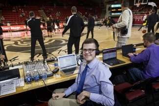 Sam Goldfarb at a basketball game with a headset and laptop on the sidelines
