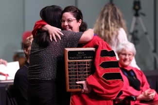 Two people hugging onstage at Convocation