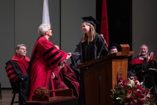 Student shaking hand of Shelley Rigger at Convocation