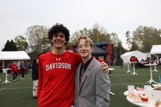 Two students smiling with football field in background