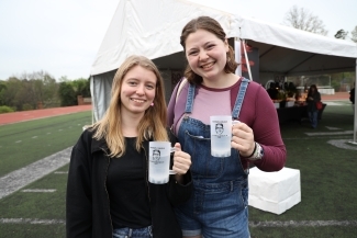 Two students holding plastic cups of water and smiling