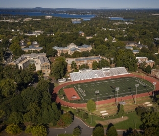 an aerial view of Davidson College campus with a football field in the foreground and a lake in the background