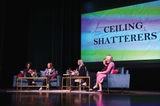 Group of women seated onstage in front of screen that reads "Ceiling Shatterers."