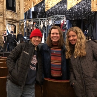a group of three white women smiling in a theater