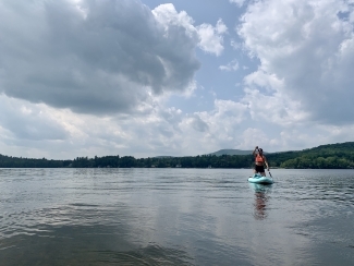 a young woman sits on a paddleboard on a lake