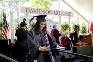 a young woman holds up her diploma looking at it 