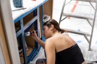 Student painting cabinetry navy blue