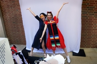 two young women strike a pose in front of a white sheet