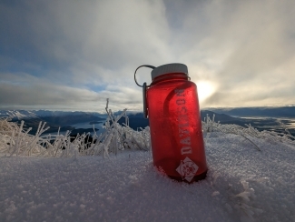 a water bottle sitting in a pile of sand on a sunny day