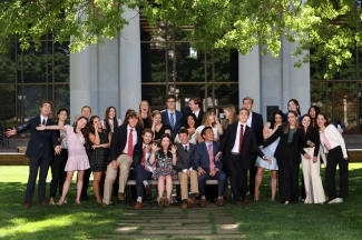a large group of students in business formal making silly faces and smiling