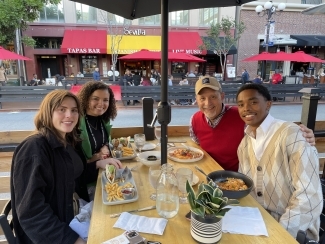 a group of students and their professor together at a restaurant and smiling