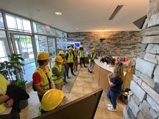 a group of students in construction helmets and vests walking around a modern space