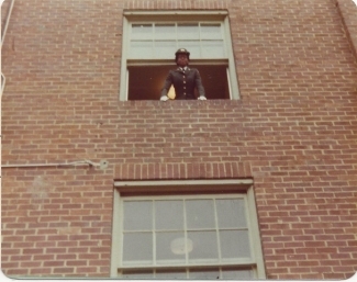 a young Black woman leans out a window