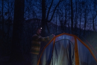 a student pitches a tent at sunset