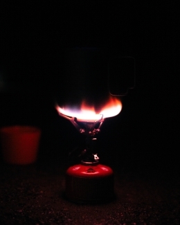 a compact stove lit up at night on a camping trip