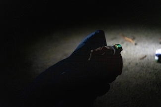 a young camper laying on their back staring up at the sky while wearing headlamp