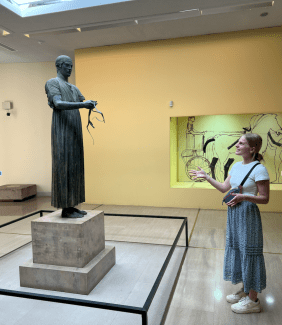 Maggie Matuszak (’27) poses with her presentation subject, The Charioteer, Archaeological Museum of Delphi
