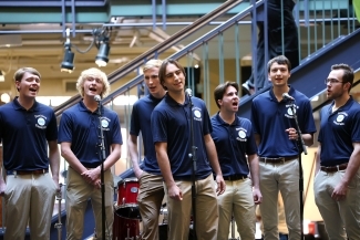 A group of young men singing in blue polos emblazoned with "DAVIDSON GENERALS"
